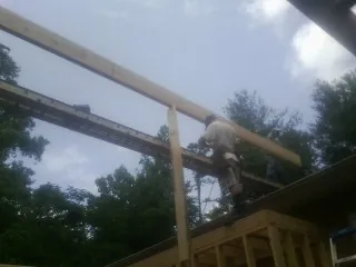 Carpenter setting a ridge beam over a new addition frame — Ice Dam Removal by Roofing Brothers in Sodus