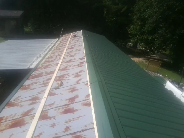 Old rusted panels beside newly installed green metal roofing — Wind Damage Roof Repair by Roofing Brothers in Sodus